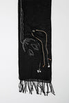 De duurzame, handgemaakte, betekenisvolle Tulip sjaal in zwart die elegant gedrapeerd is en een intrigerend patroon van verweven kleuren en texturen laat zien