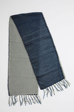 De duurzame, handgemaakte, betekenisvolle Duo sjaal in donkerblauw en grijs die elegant gedrapeerd is en een intrigerend patroon van verweven kleuren en texturen laat zien