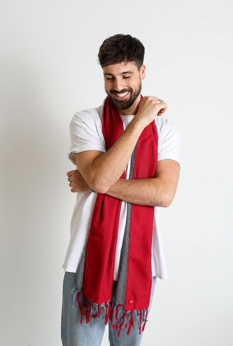 De duurzame, handgemaakte, betekenisvolle Duo sjaal in rood en grijs die elegant gedrapeerd is en een intrigerend patroon van verweven kleuren en texturen laat zien