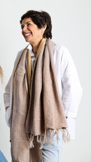 De duurzame, handgemaakte, betekenisvolle Plain sjaal in zalm die elegant gedrapeerd is en een intrigerend patroon van verweven kleuren en texturen laat zien