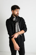 De duurzame, handgemaakte, betekenisvolle Duo sjaal in zwart en grijs die elegant gedrapeerd is en een intrigerend patroon van verweven kleuren en texturen laat zien