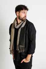 De duurzame, handgemaakte, betekenisvolle Duo sjaal in zwart en creme die elegant gedrapeerd is en een intrigerend patroon van verweven kleuren en texturen laat zien