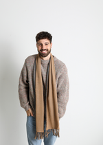 De duurzame, handgemaakte, betekenisvolle Duo sjaal in beige en grijs die elegant gedrapeerd is en een intrigerend patroon van verweven kleuren en texturen laat zien