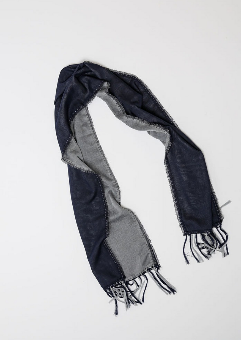 De duurzame, handgemaakte, betekenisvolle Duo sjaal die elegant gedrapeerd is en een intrigerend patroon van verweven kleuren en texturen laat zien